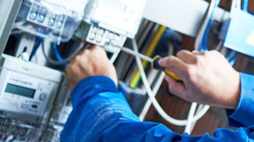 Elektroniker Hände die an einem Verteilerkasten arbeiten