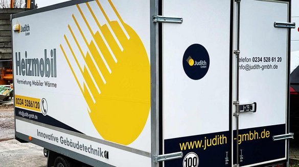 Ein Heizmobil mit auffälligem gelbem Design steht auf einem Baustellengelände, um mobile Wärme anzubieten.