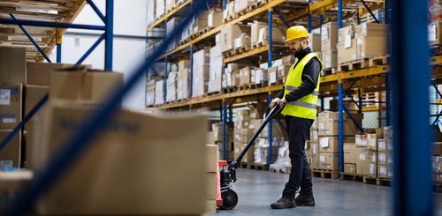 Eine Lagerhalle mit einem Lagerist der ein Hubwagen bedient
