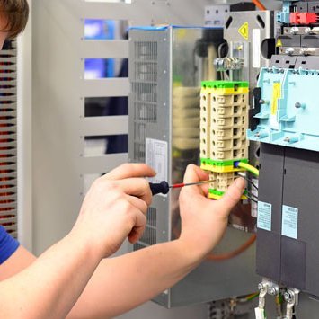 Ein Elektroniker der an einer Reihenklemme schraubt