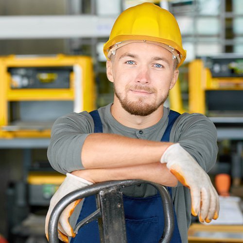 Ein Bauhelfer der sich an einem Hubwagen anlehnt