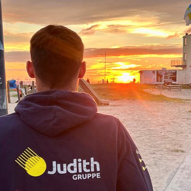 Der Sonnenuntergang malt den Himmel in warmen Farben, während ein junger Mann mit dem Rücken zur Kamera schaut.
