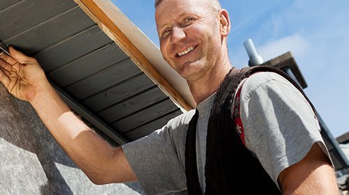 Ein Dachdecker der an einem Dach arbeitet
